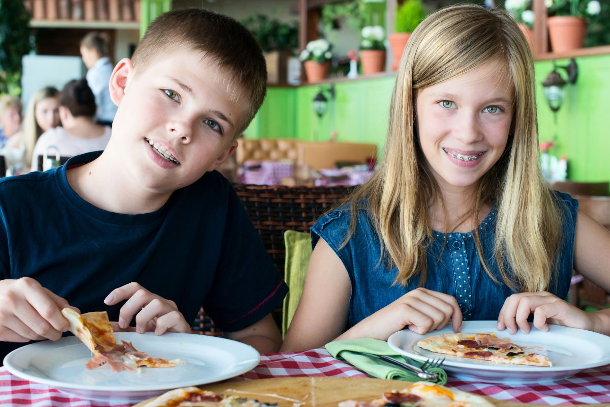 Best and Worst Holiday Foods for Braces Two children painting at a table in a bright, colorful room with artwork displayed on walls.