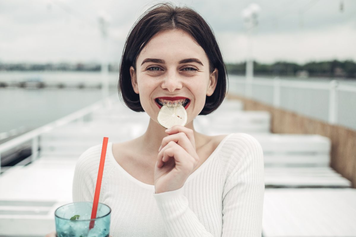 Young woman smiling while eating ice cream near water on sunny day